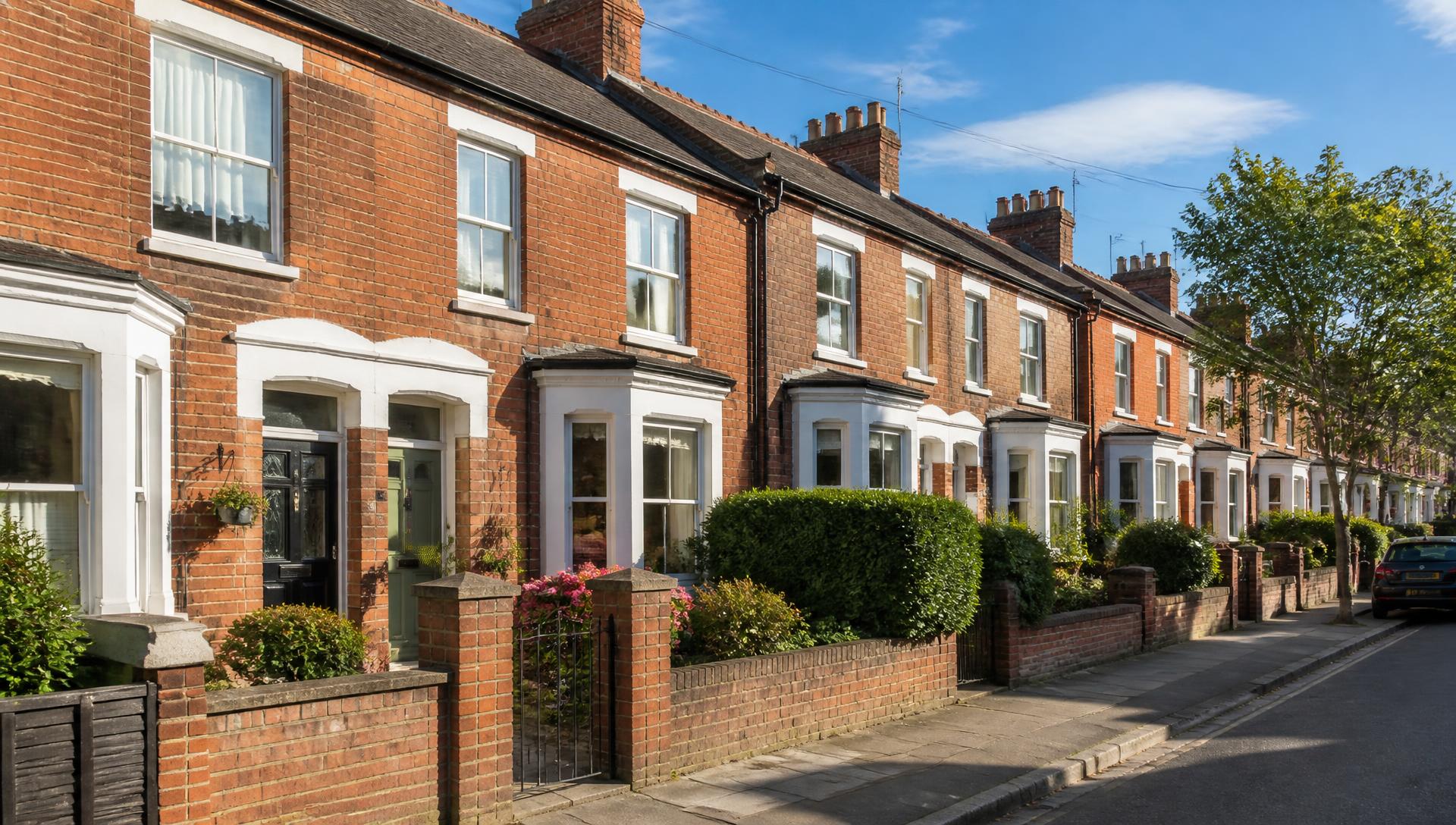 A row of well-kept British brick terraced rental houses on a quiet sunny street