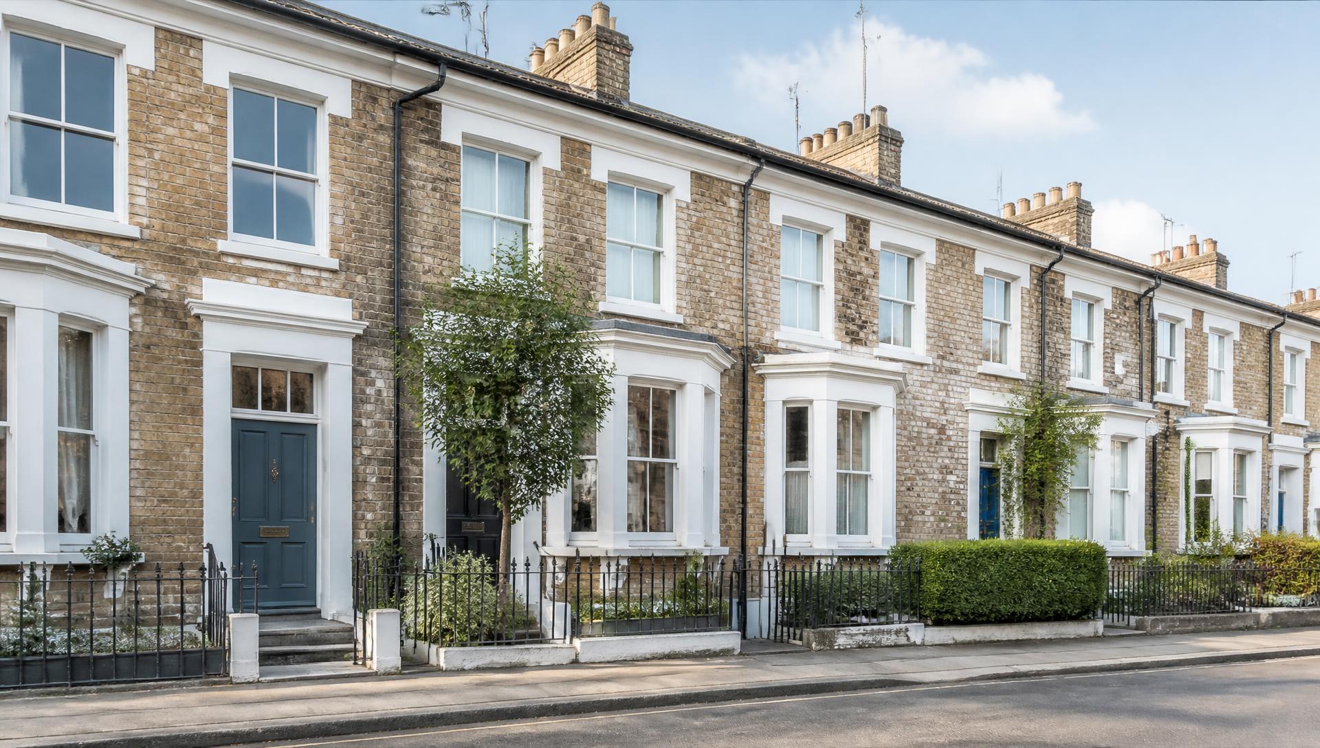 A row of well-kept British brick terraced rental houses on a quiet street